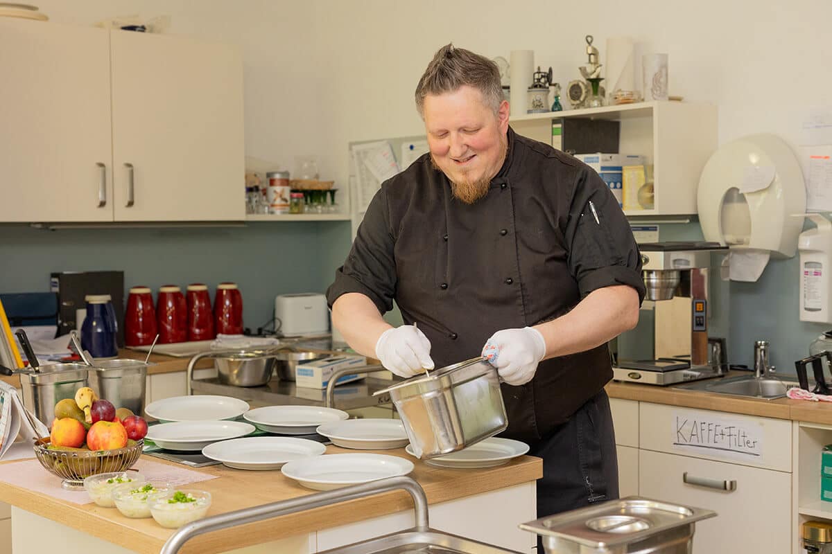 Koch bereitet Mahlzeiten für die Bewohner des Aschrottheims zu